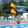 Families and children enjoying a community swimming pool with a corkscrew water slide